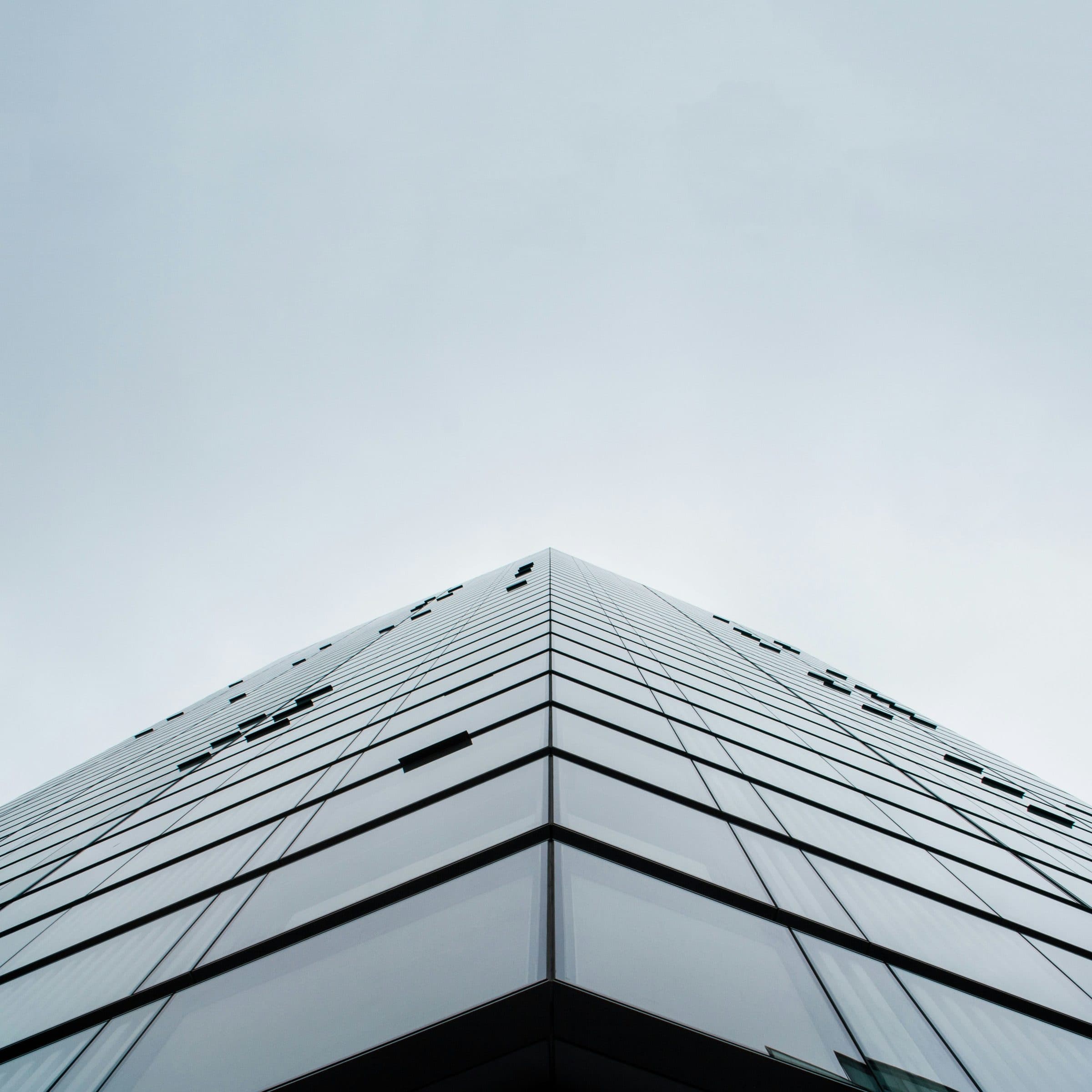 Corner of a glass building against a pale sky