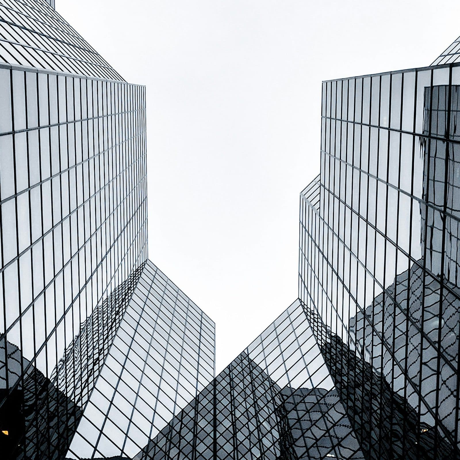 Glass towers seen from below framing a white sky