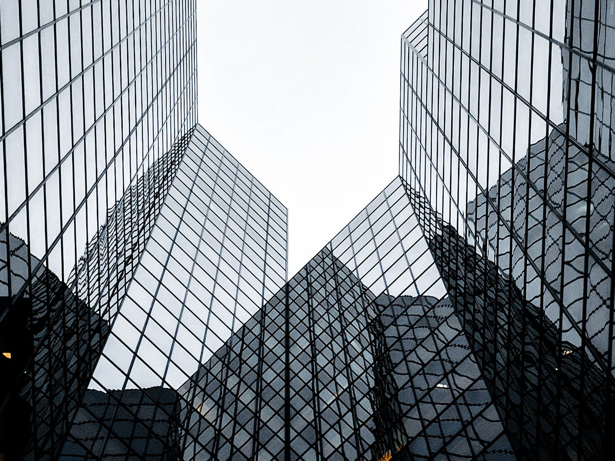 Glass buildings framing a pale sky, seen from below